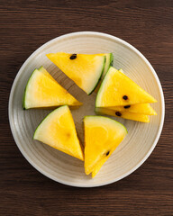 Sliced yellow watermelon pattern flat lay on wooden table background.
