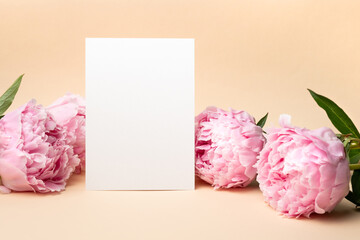 Blank invitation or greeting card mockup with fresh peony flowers, white card mock up with copy space