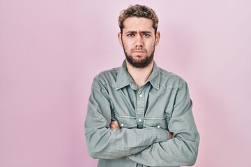 Obraz premium Hispanic man with beard standing over pink background skeptic and nervous, disapproving expression on face with crossed arms. negative person.