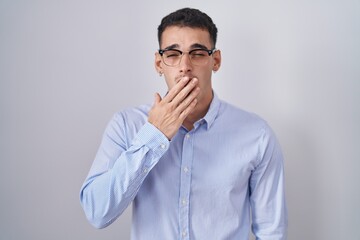Handsome hispanic man wearing business clothes and glasses bored yawning tired covering mouth with hand. restless and sleepiness.