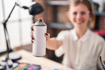 Young blonde woman artist smiling confident holding graffiti spray at art studio