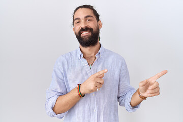 Hispanic man with beard wearing casual shirt smiling and looking at the camera pointing with two...