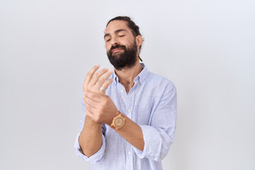 Hispanic man with beard wearing casual shirt suffering pain on hands and fingers, arthritis inflammation