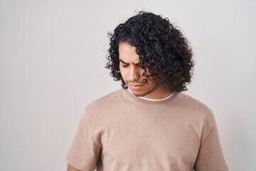Fototapeta na wymiar Hispanic man with curly hair standing over white background with hand on stomach because indigestion, painful illness feeling unwell. ache concept.