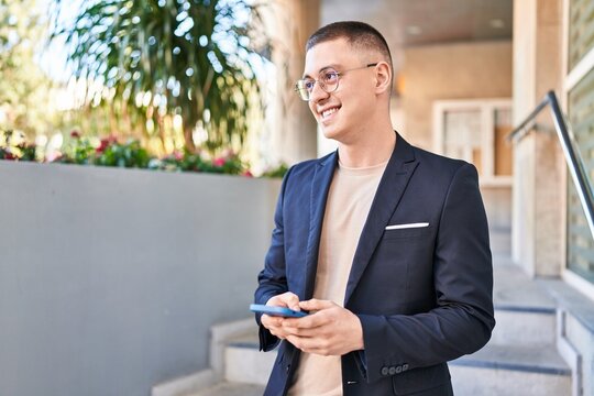 Young hispanic man executive smiling confident using smartphone at street