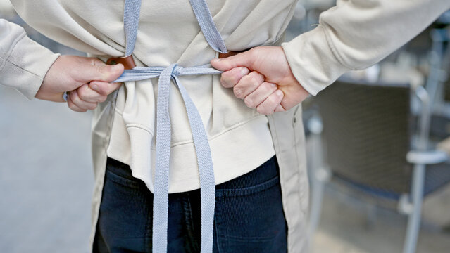 Young caucasian man waiter tying apron at coffee shop terrace - Powered by Adobe