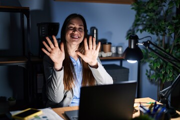 Young brunette woman working at the office at night showing and pointing up with fingers number ten while smiling confident and happy.