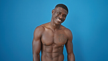 Fototapeta na wymiar African american man smiling confident standing shirtless over isolated blue background
