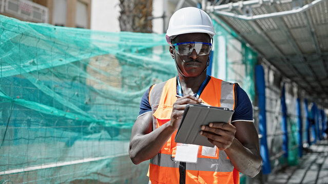 African american man builder using touchpad at construction place
