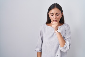 Young hispanic woman standing over white background feeling unwell and coughing as symptom for cold or bronchitis. health care concept.