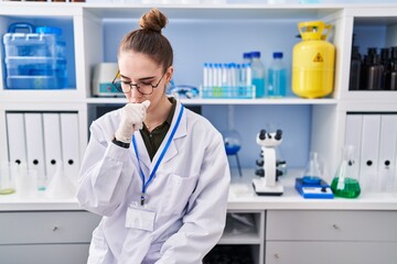 Young hispanic girl working at scientist laboratory feeling unwell and coughing as symptom for cold...