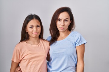 Young mother and daughter standing over white background skeptic and nervous, frowning upset because of problem. negative person.