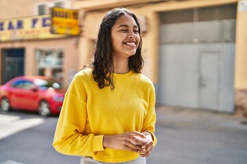 Young african american woman smiling confident holding earphones at street