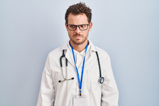 Young hispanic man wearing doctor uniform and stethoscope skeptic and nervous, frowning upset because of problem. negative person.
