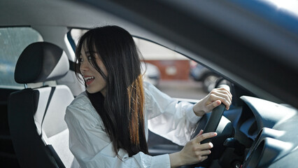 Young chinese woman smiling confident driving car at street