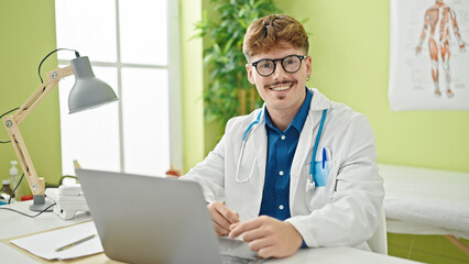 Young hispanic man doctor using laptop wearing glasses at the clinic