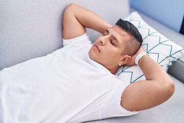 Young latin man lying on sofa sleeping at home