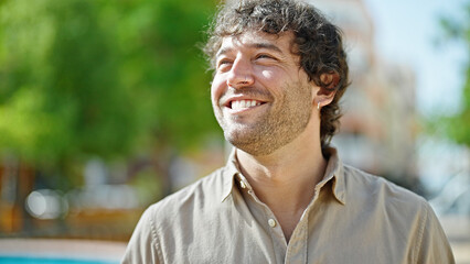 Young hispanic man smiling confident looking to the side at park