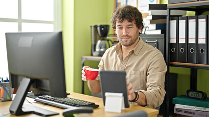 Young hispanic man business worker drinking coffee at office