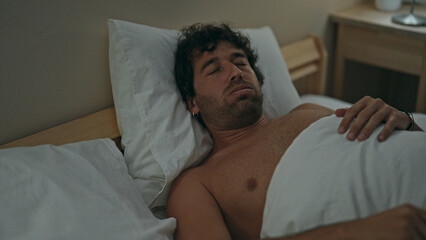 Young hispanic man lying on bed sleeping shirtless at bedroom