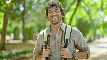 Young hispanic man tourist wearing backpack smiling at park