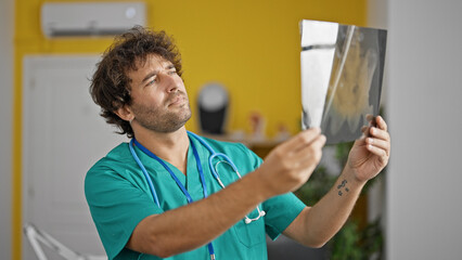 Young hispanic man doctor looking xray at clinic