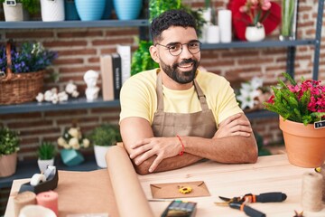 Young arab man florist smiling confident sitting with arms crossed gesture at florist