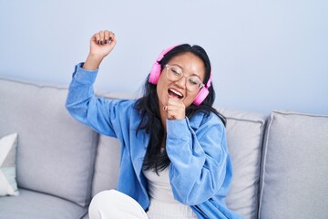 Young chinese woman listening to music singing song at home