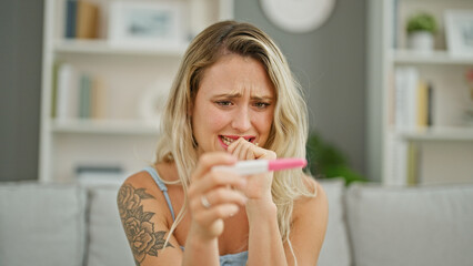 Young blonde woman waiting for pregnancy result test nervous at home