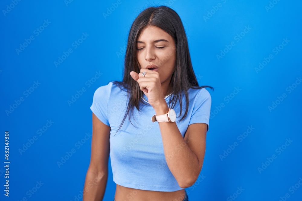 Sticker Brunette young woman standing over blue background feeling unwell and coughing as symptom for cold or bronchitis. health care concept.