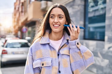 Fototapeta premium Young beautiful hispanic woman smiling confident listening audio message by the smartphone at street