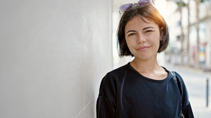 Young beautiful hispanic woman standing with serious expression at street
