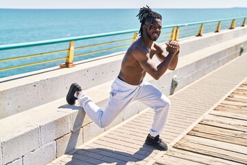 African american woman shirtless training legs exercise at seaside