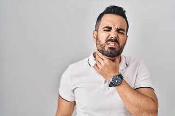 Young hispanic man with beard wearing casual clothes over white background touching painful neck, sore throat for flu, clod and infection