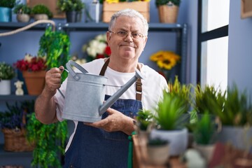 Middle age grey-haired man florist watering plant at florist © Krakenimages.com