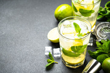 Mojito with rum and lime on black background. Traditional Summer iced drink.