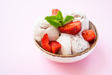 Homemade ice cream with fresh strawberries on pink background. Close up.