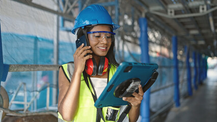 African american woman builder talking on smartphone using touchpad at street