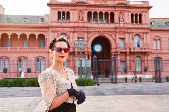 caucasian actrees woman dressed in vintage clothes in the street with The Casa Rosada in the background	