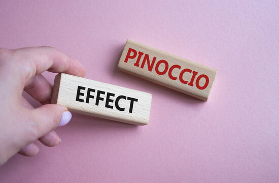 Pinoccio Effect symbol. Concept word Pinoccio Effect on wooden blocks. Businessman hand. Beautiful pink background. Business and Pinoccio Effect concept. Copy space