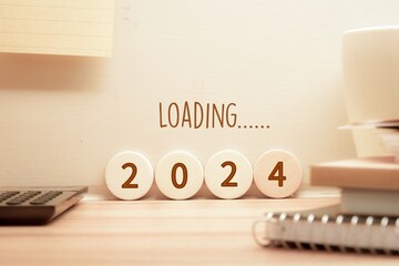 2024 loading inscription on wooden blocks and wall on study desk. New year start concept.