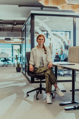 Fototapeta na wymiar A modern businesswoman with striking orange hair sitting confidently in a contemporary office, accompanied by her laptop, embodying professionalism, creativity, and success in a technology-driven
