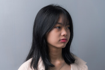 Young beautiful Asian teenage girl showing a sad, disappointed expression on background.