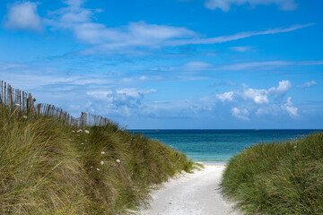 A dreamlike sandy path leads through green dunes to the turquoise sea in the north of Brittany...