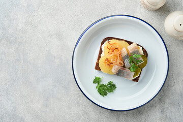 Open sandwich or smorrebrod with rye bread, herring, eggs, caramelized onions, parsley and cottage cheese on old wooden rustic table backgrounds. Danish or Scandinavian traditional food snack lunch.