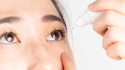 Woman applying artificial tear eye drop for relief dry eyes, irritated eye, conjunctivitis or...