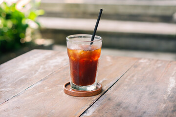 transparent glass of ice black coffee or americano on wooden table with selective focus in cafe restaurant