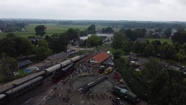 Beekbergen, the Netherlands - August 6th, 2023: Descending drone footage of people lining up to see a steam locomotive on the local marshalling yard before it leaves on a trip to nearby Dieren.