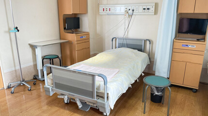 A multi-bed hospital room with an empty bed ready for a new patient with a cabinet, TV, and hospital equipment in a Japanese hospital. 