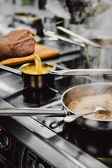 Chef hands cooking cheese sauce in the restaurant kitchen